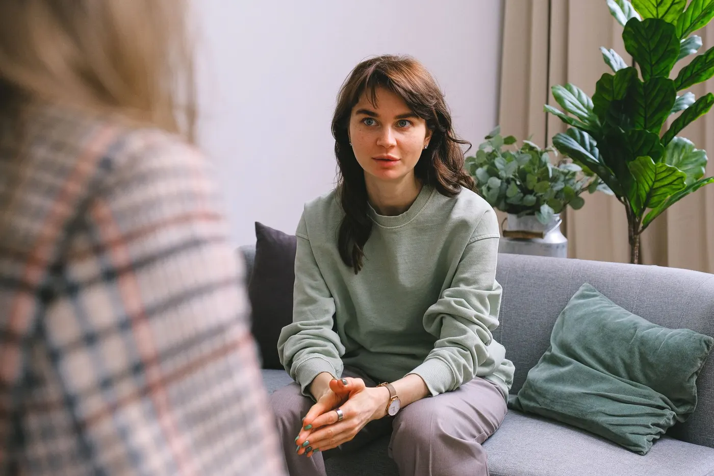 Femme assise sur un canapé, à l'écoute, lors d'un premier entretien avec une thérapeute